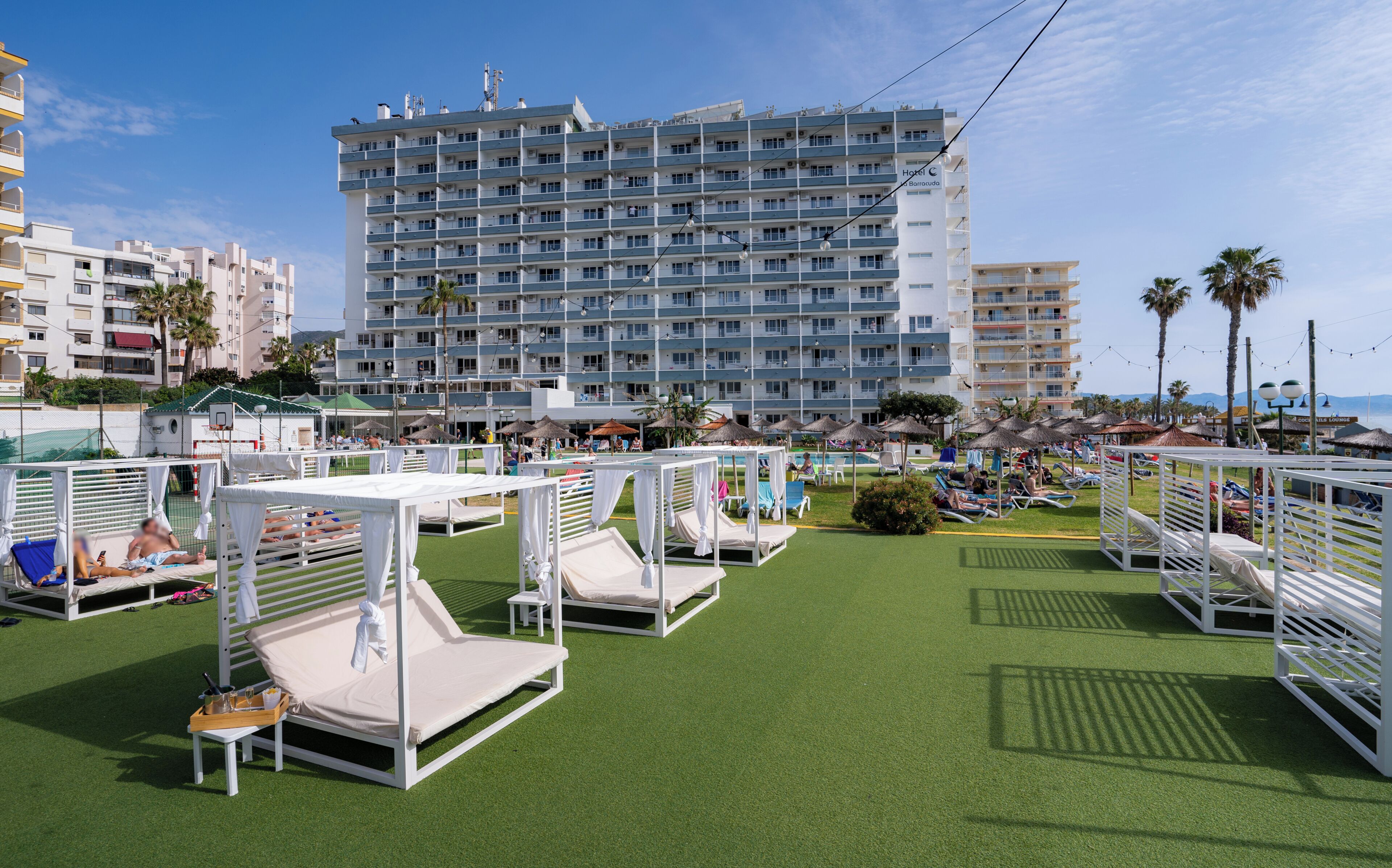A hotel with multiple floors, outdoor seating areas with umbrellas, and a pool.