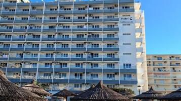 A hotel with multiple balconies, a swimming pool, and sun loungers.
