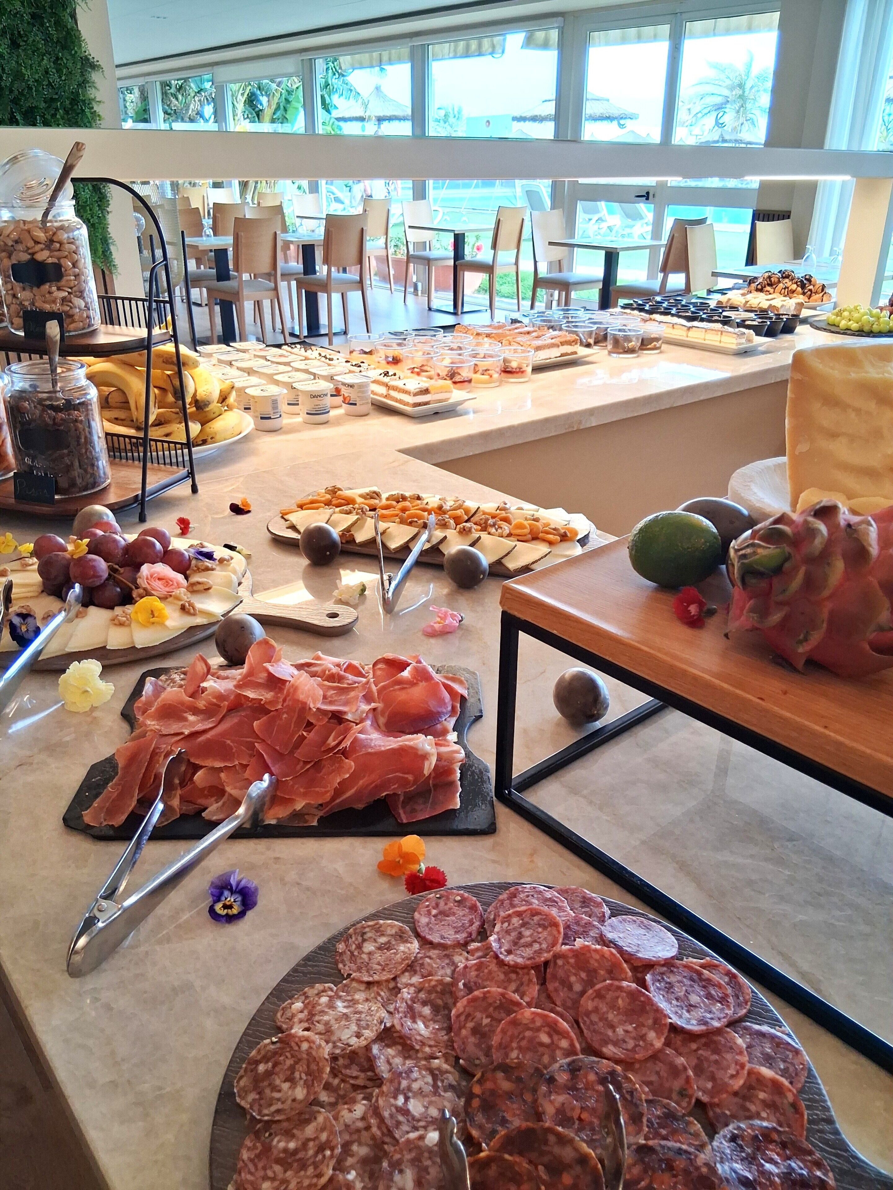 Un bufé con diferentes opciones de comida, incluyendo carnes, quesos y frutas.