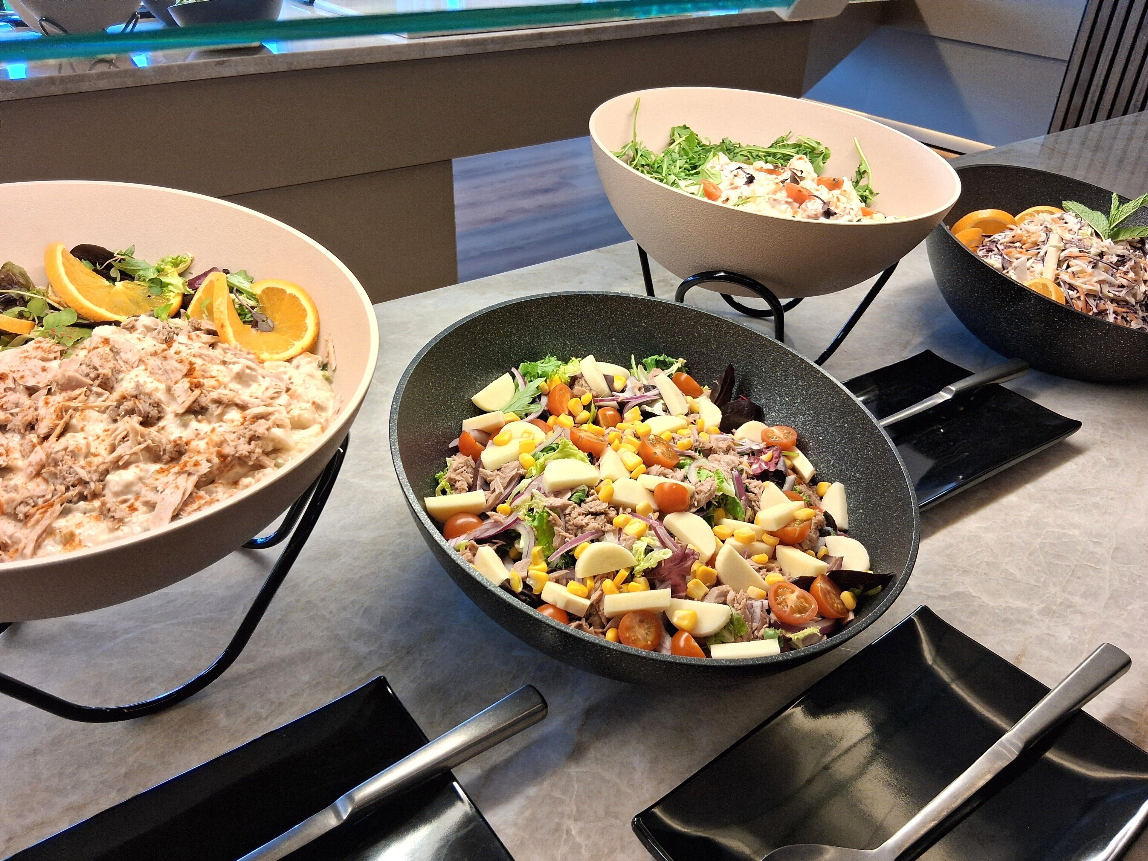 A variety of dishes on a table, including salads and a creamy dish with shredded meat.