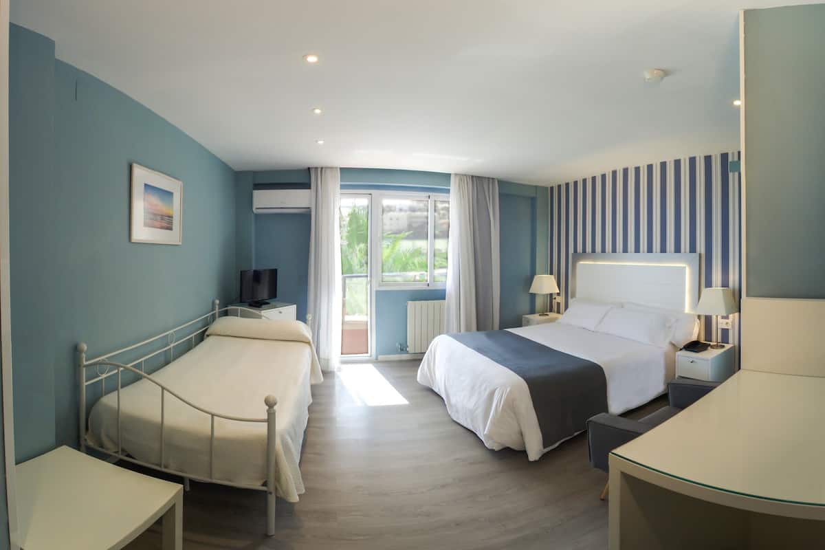 Una habitación de hotel con dos camas, televisión, escritorio y ventana con cortinas.
