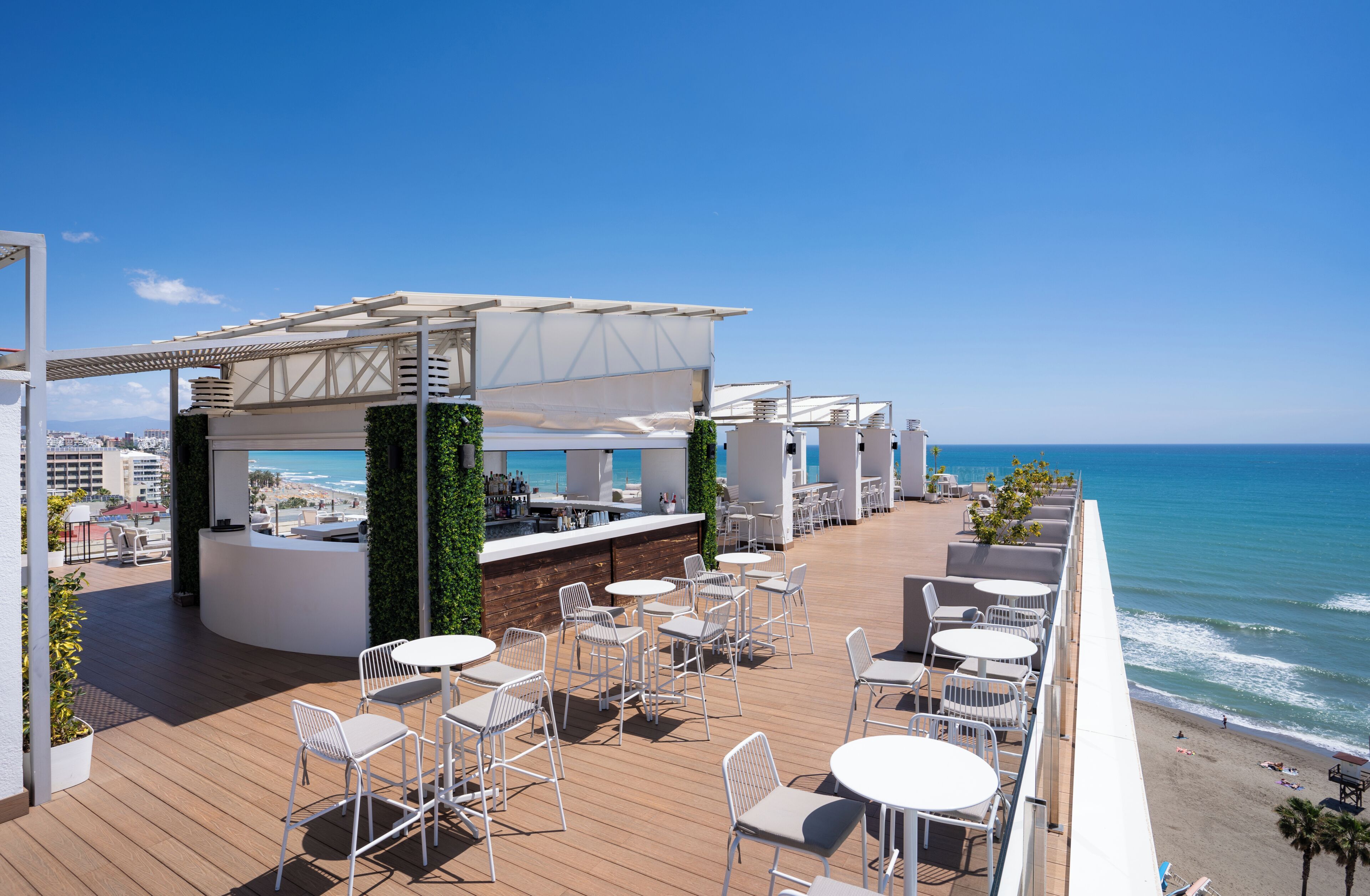 A rooftop terrace with outdoor seating, a bar area, and a view of the ocean.