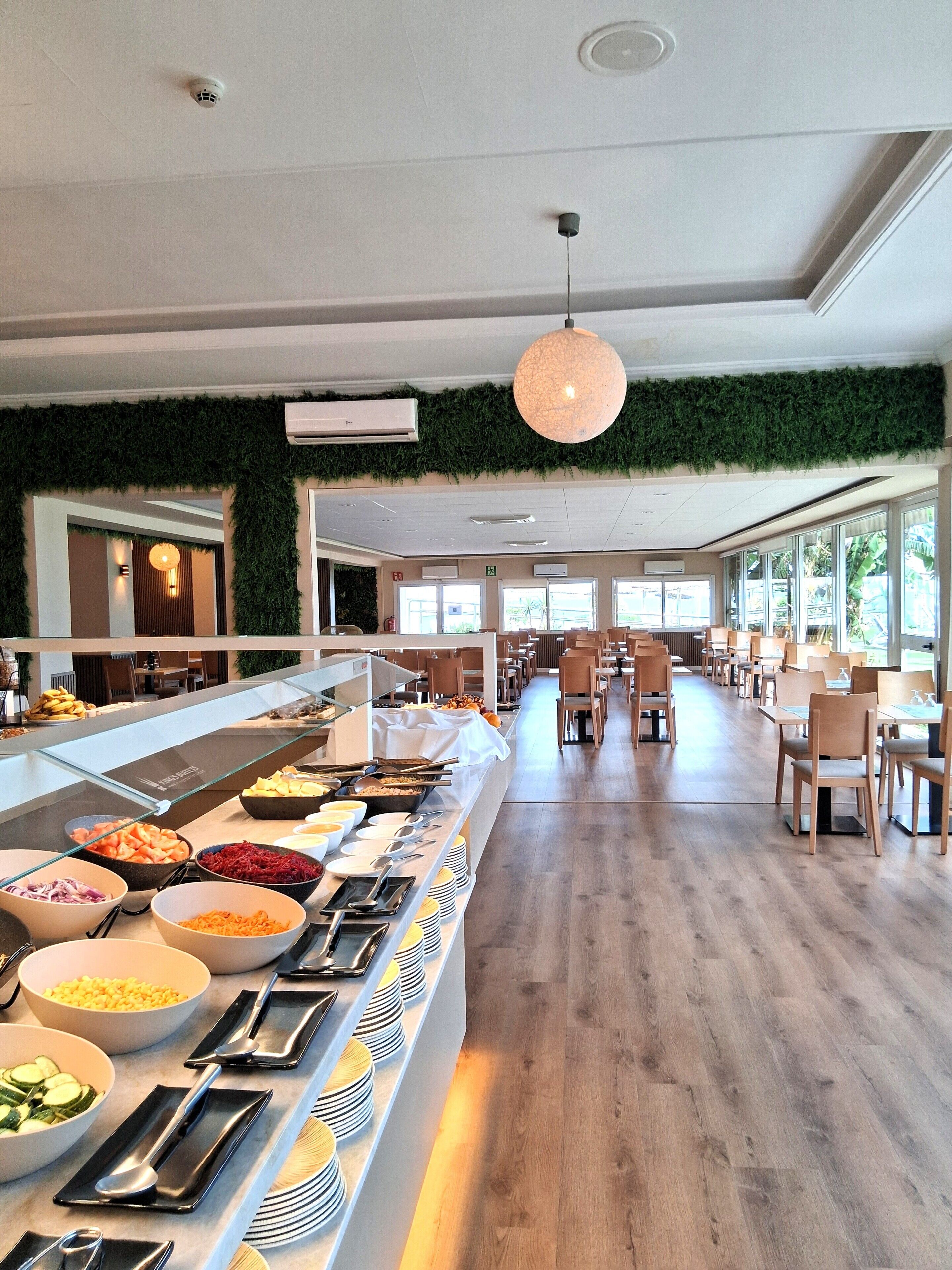 A buffet area with various food items, a long counter, and a seating area with tables and chairs.