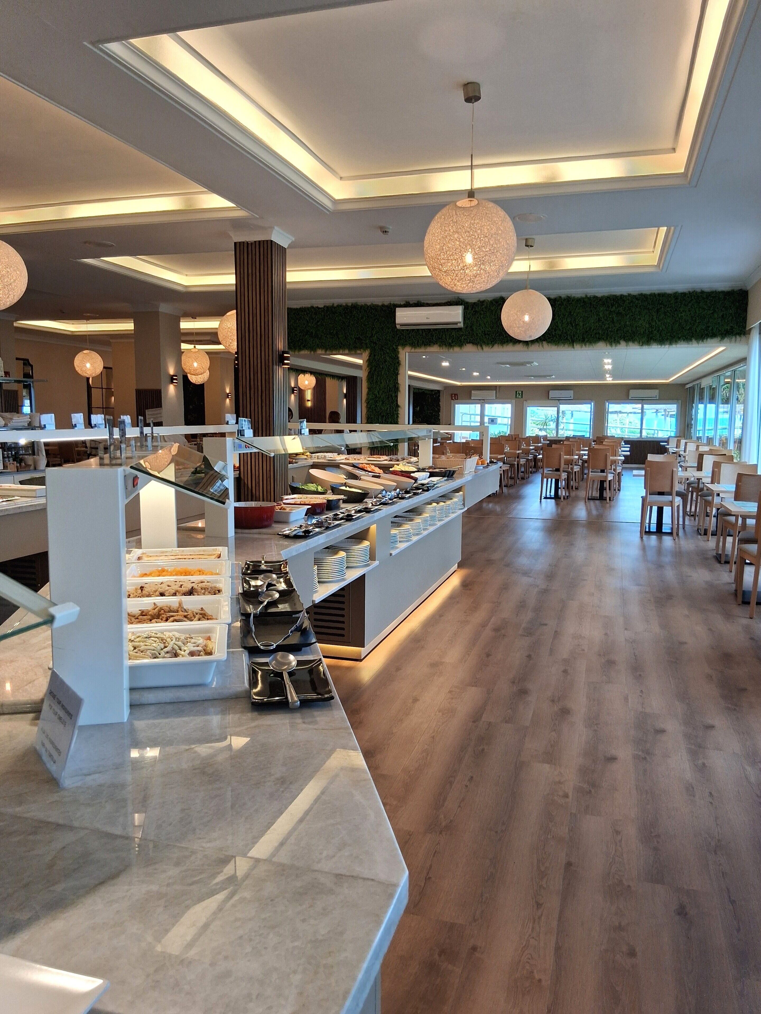 Zona pranzo moderna con buffet, pavimento in legno e illuminazione a sospensione.