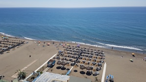 A beach with rows of sunbeds and umbrellas, a clear sky, and the ocean. - Hotel La Barracuda (Torremolinos)