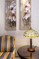 A room with striped armchairs, a table with a decorative lamp, and two wall art pieces featuring flowers and text.