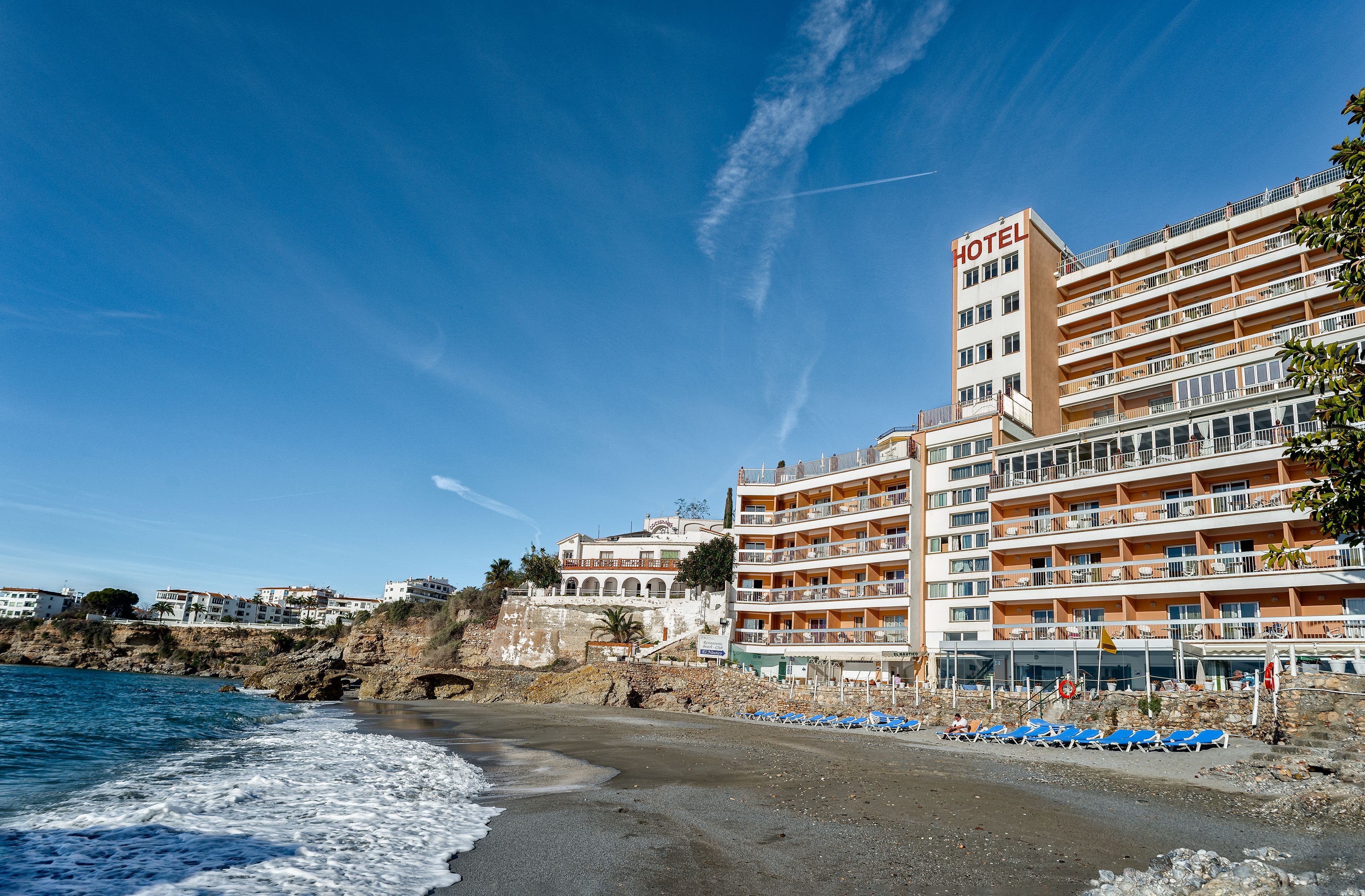 A hotel with multiple balconies, a beachside location, and a view of the sea.