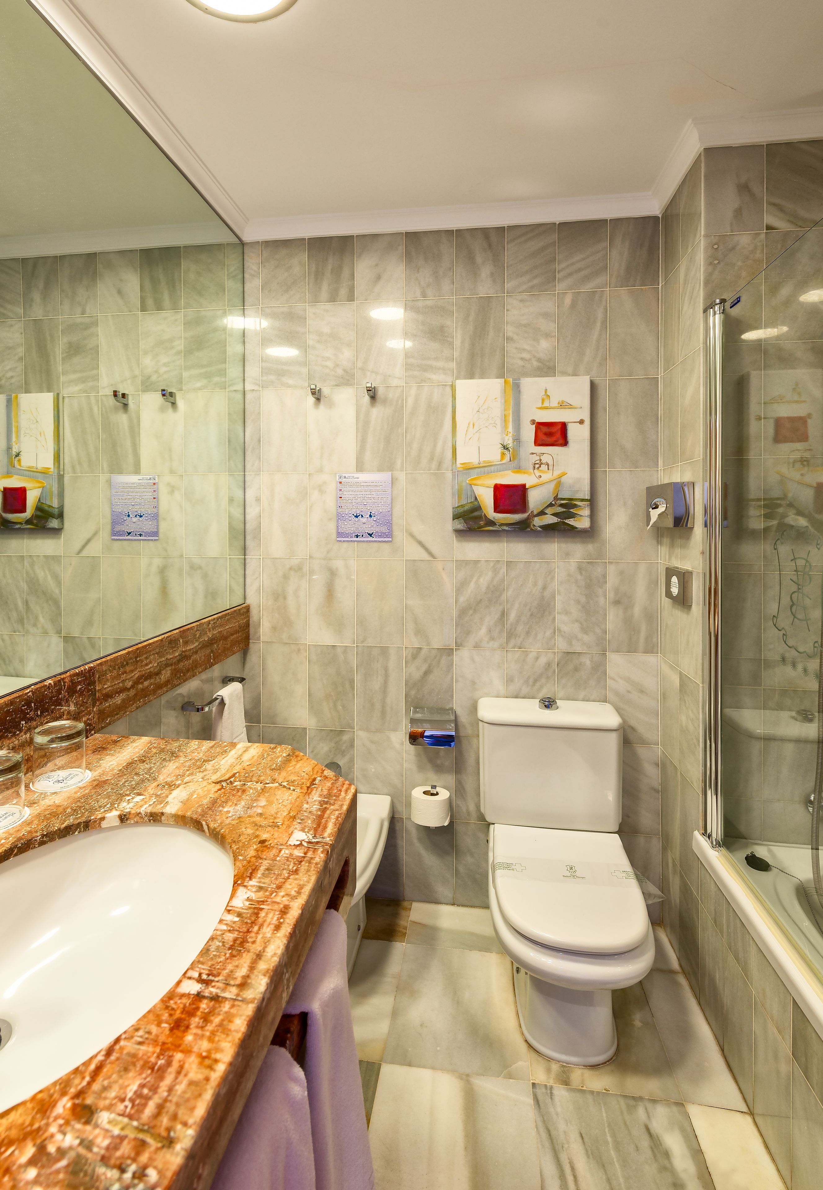 A bathroom with a marble sink, toilet, and glass-enclosed shower.