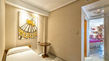 A hotel room with a bed, a small round table, and a painting on the wall.