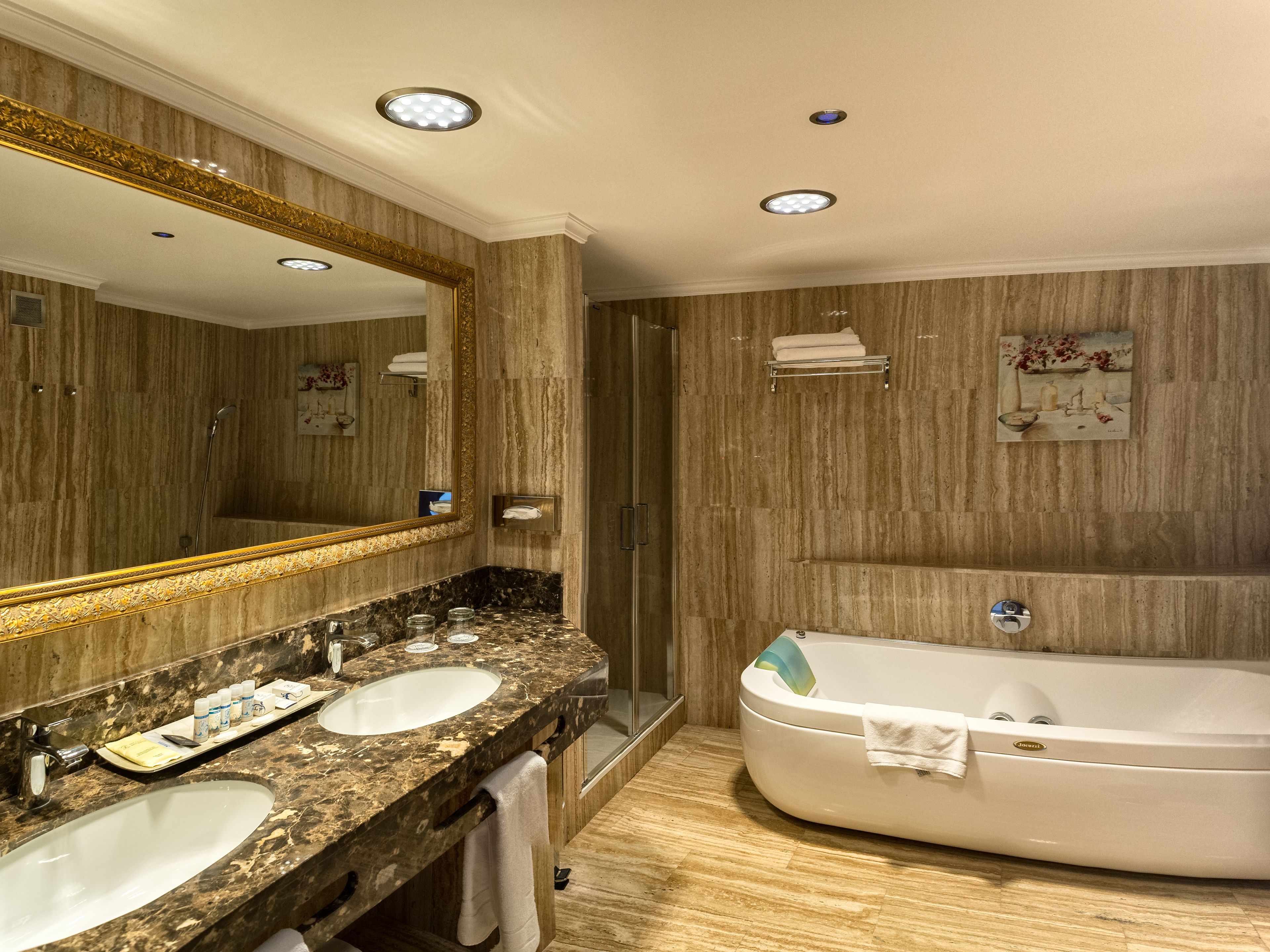 A bathroom with two sinks, a large mirror, a bathtub, and a shower.