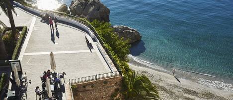 Terraza frente al mar con mobiliario exterior, con vistas a la playa y al océano.
