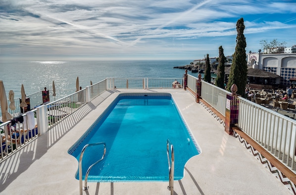 Piscina all'aperto, una piscina a sfioro, lettini