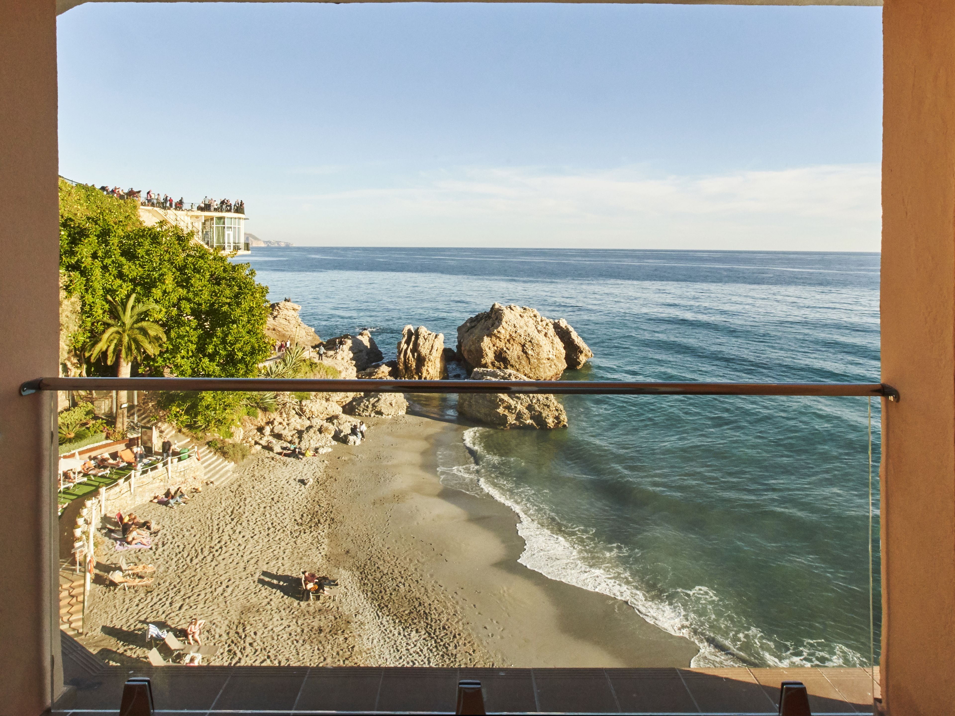 Un balcón con vista a una playa rocosa y al mar.