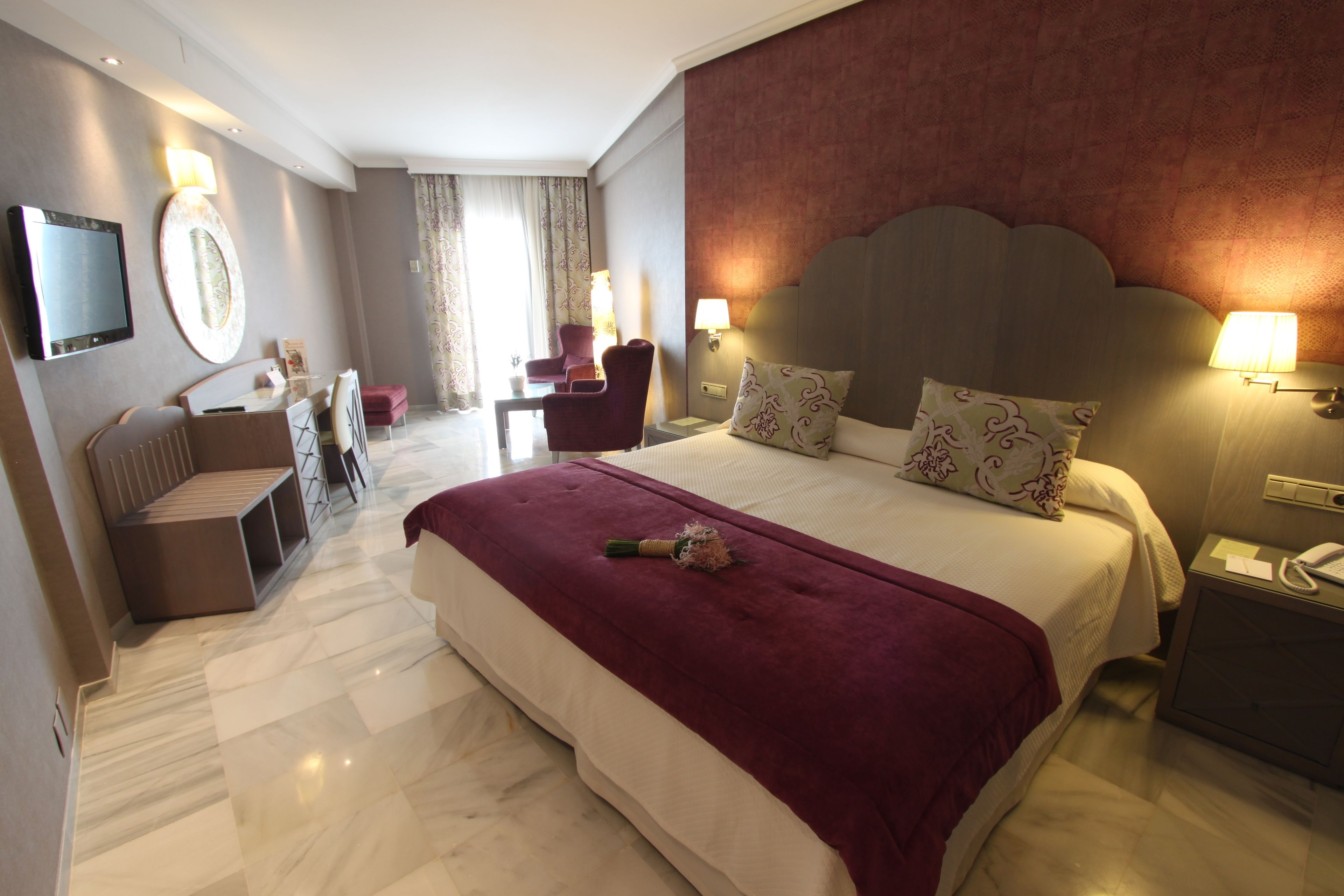 Une chambre d’hôtel avec un grand lit, un bureau, une chaise, une télévision et une lampe.