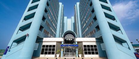 A hotel with a symmetrical facade, featuring a central entrance with a sign that reads "HOTEL" and "AMAZONS DE GUARANTIA".