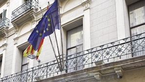 A hotel entrance with a glass facade, a metal balcony railing, and a flag. - Hotel Gaudí (Barcelona)