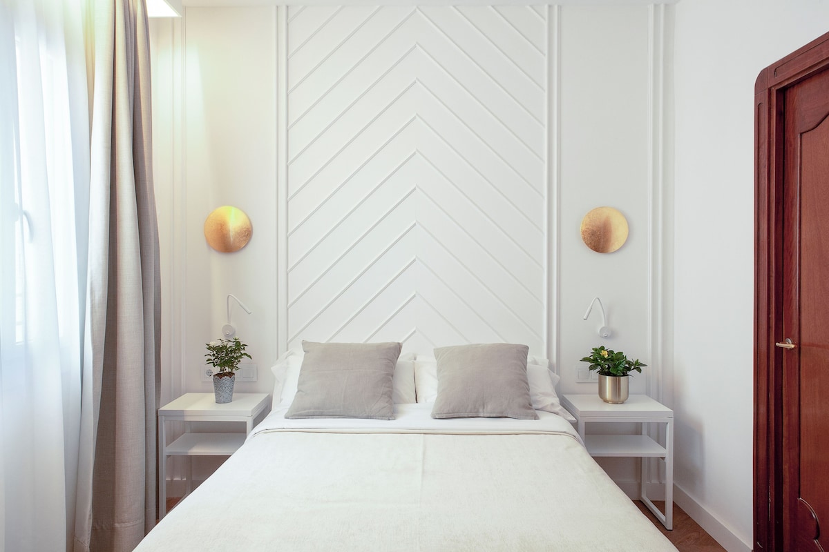 A neatly arranged bedroom with a large bed, two bedside tables, and a wooden door.