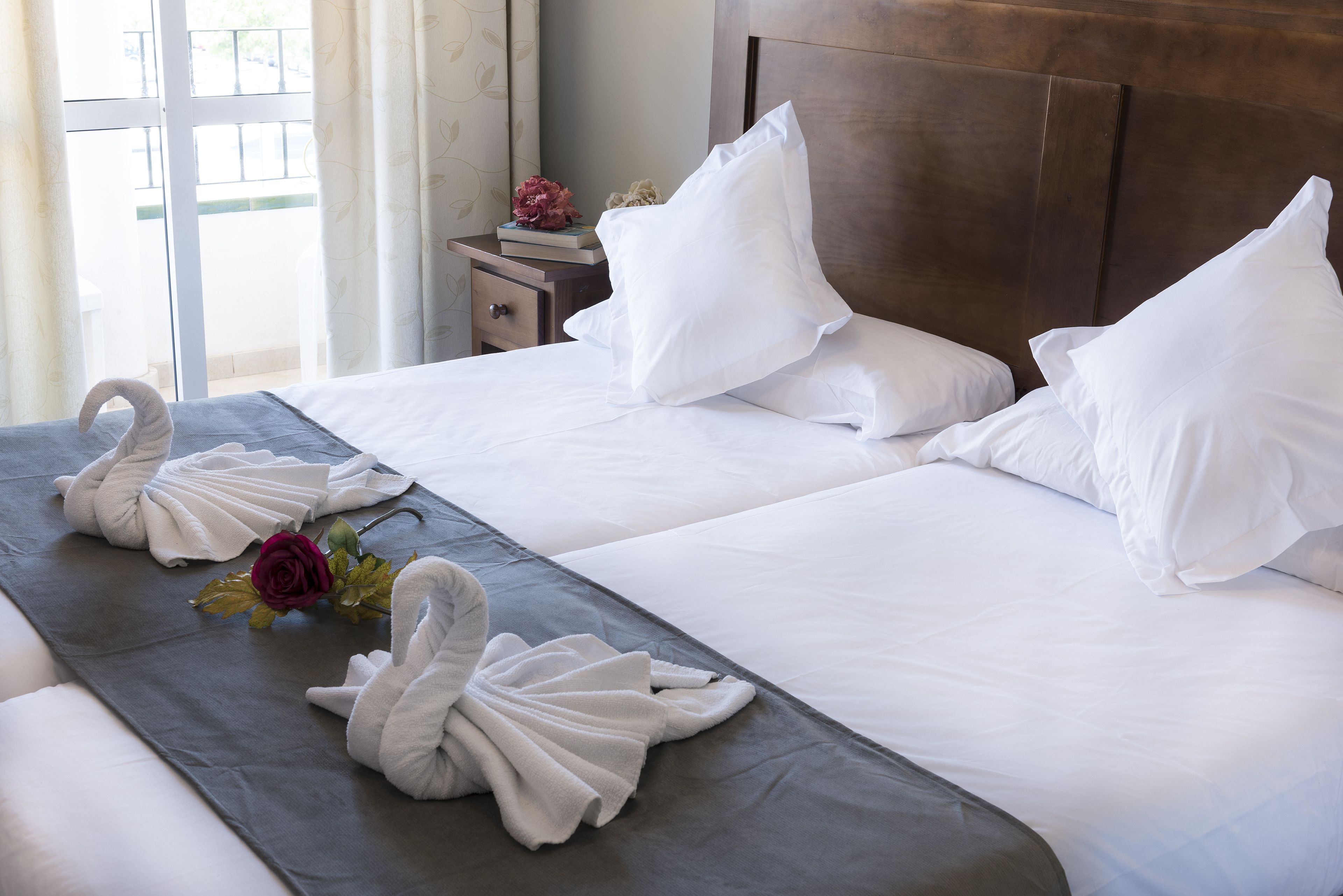 Een hotelkamer met twee bedden, witte lakens en handdoeken gevouwen in de vorm van zwanen.