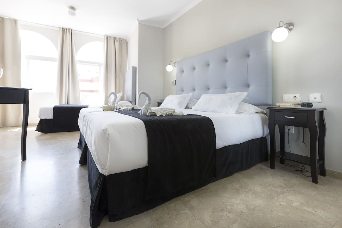Une chambre d’hôtel avec un grand lit, une table de chevet, un bureau et une chaise.