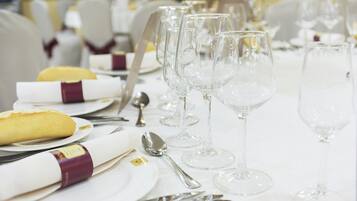 A table set for a formal event with clear glassware, folded napkins, and a bread roll.