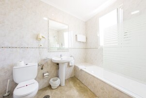 Une salle de bain avec des toilettes, un lavabo et une baignoire.