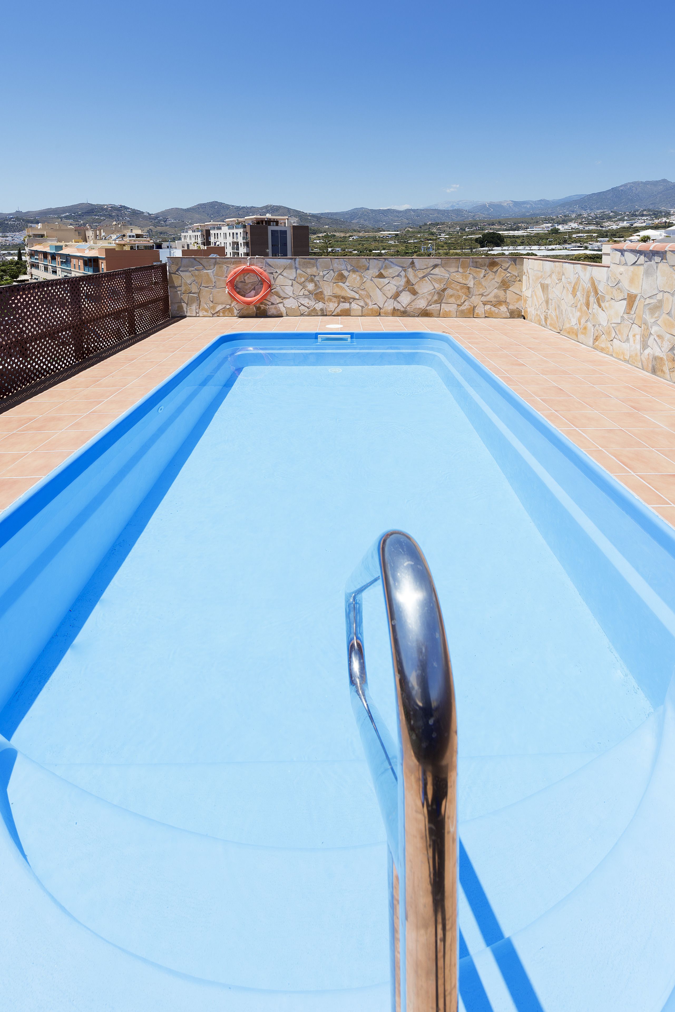 A swimming pool with a view of buildings and mountains in the background.