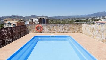 A swimming pool with a view of buildings and mountains in the background.