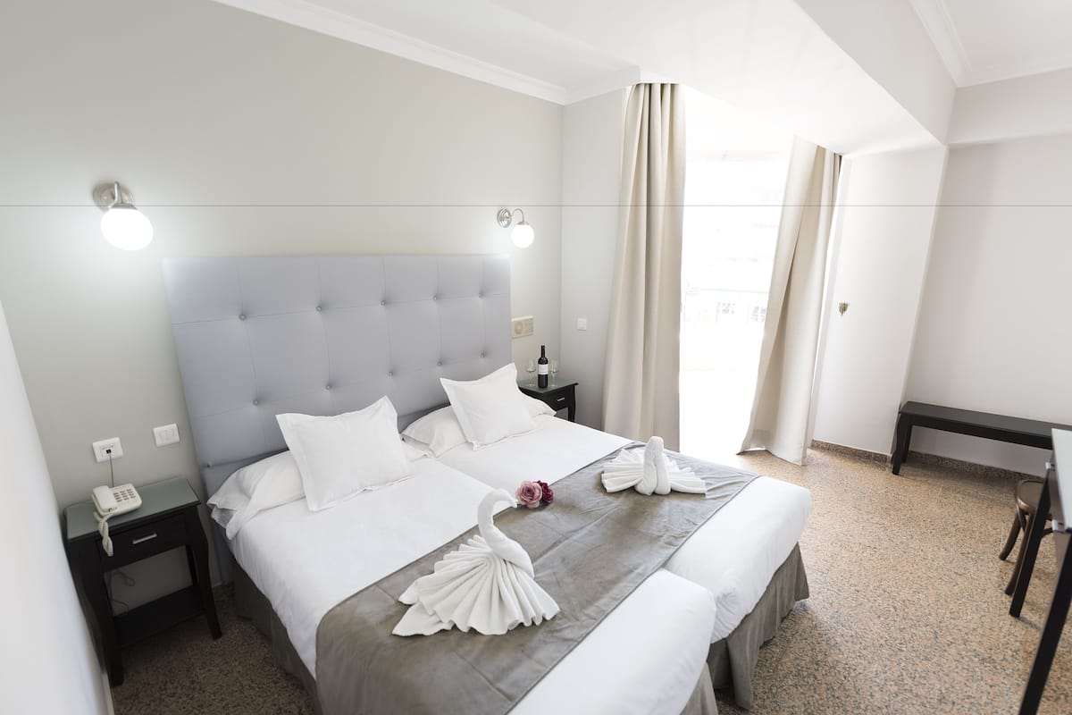 Une chambre d’hôtel avec un grand lit, une table de chevet avec un téléphone, un bureau et une chaise.