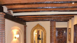 A staircase with a wooden handrail, a wall-mounted mirror, and a door with intricate carvings. - Hotel Toboso Chaparil (Nerja)