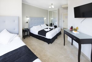 Et hotelværelse med to senge, et skrivebord, et fjernsyn og et spejl.