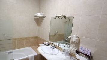 Ein Badezimmer mit Badewanne, Waschbecken, Spiegel und Dusche.