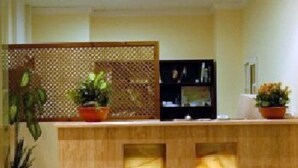 A reception desk with two illuminated panels, a wooden counter, and potted plants. - La Luna Blanca (Torremolinos)