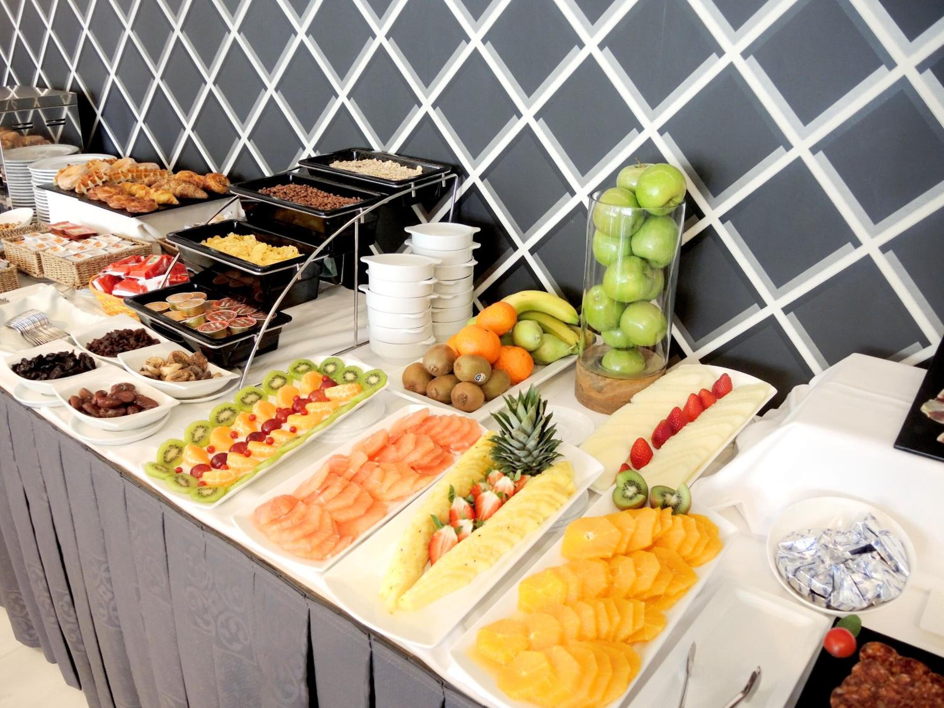 A buffet with various fruits, vegetables, and pastries.