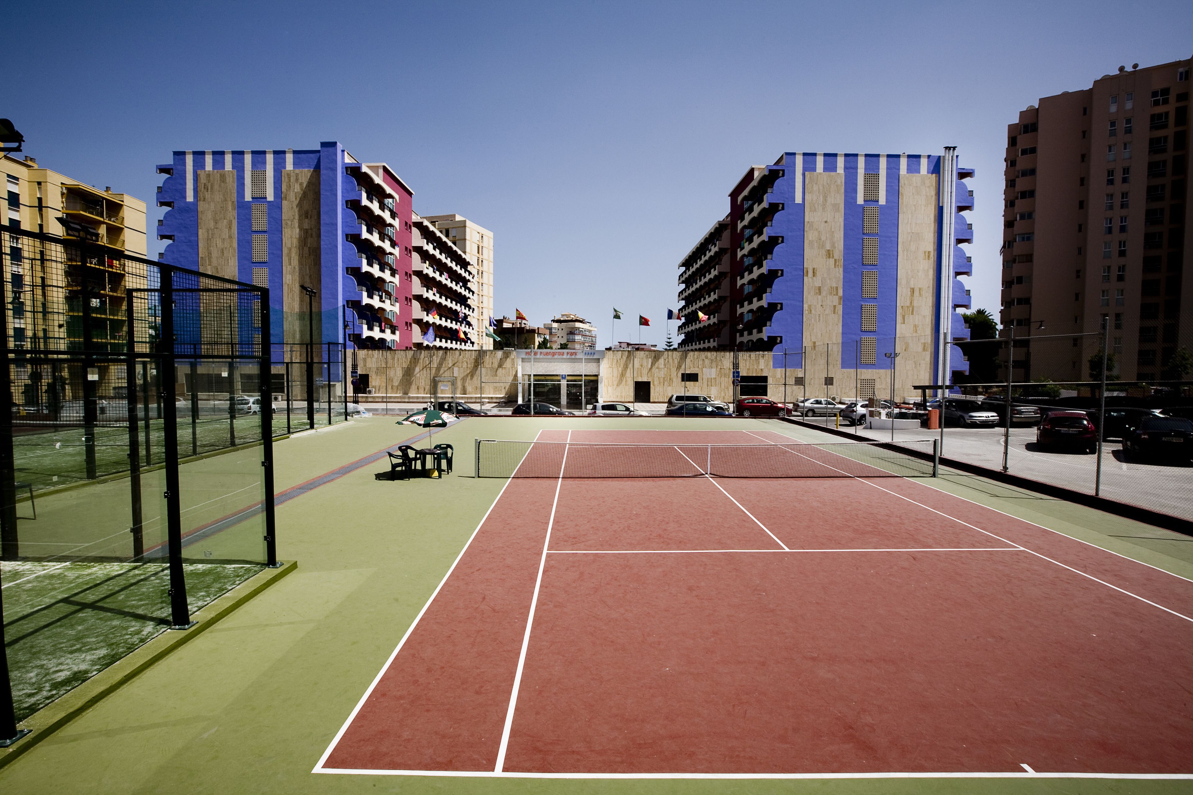 A tennis court with a net, surrounded by buildings.