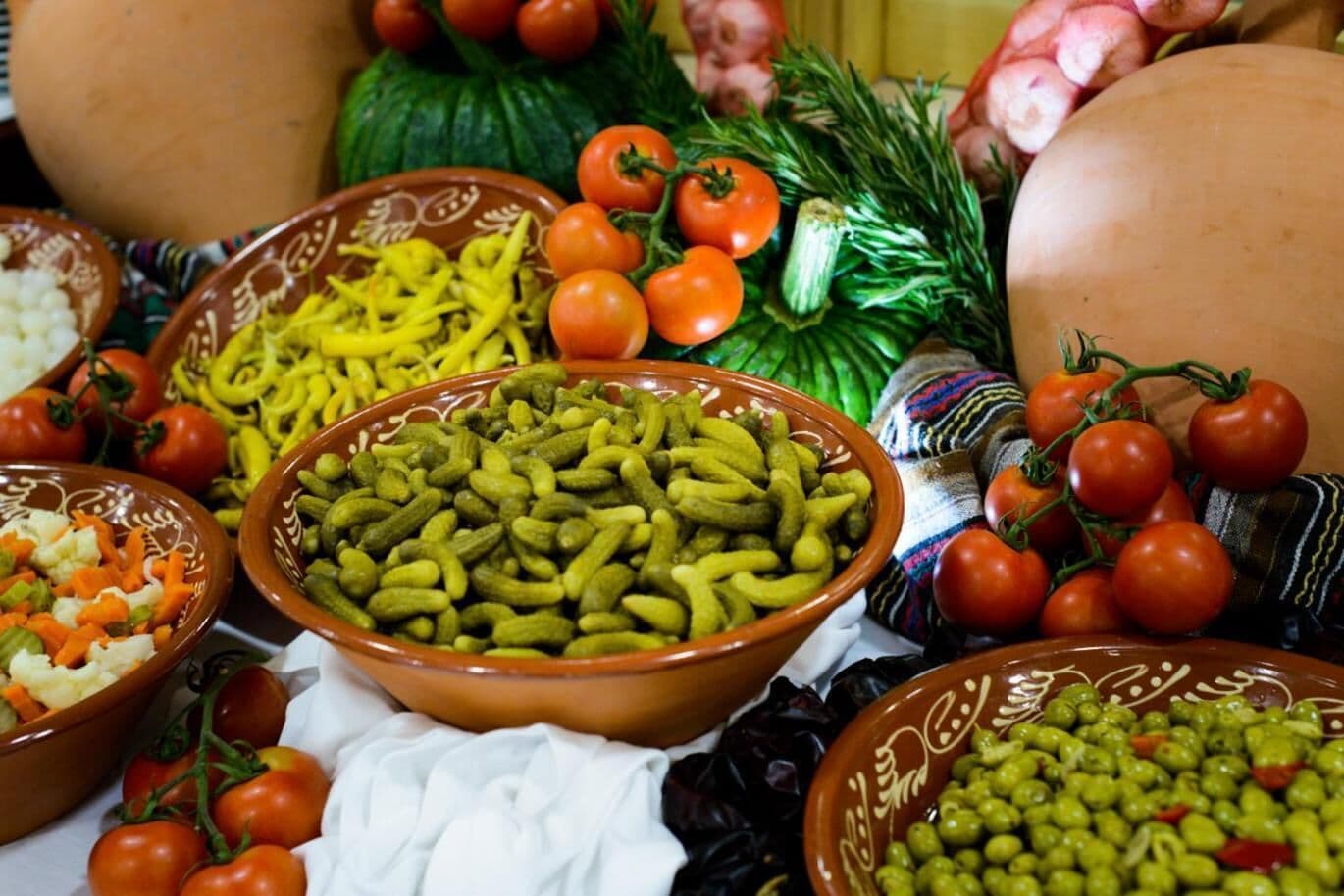 Una variedad de platos que incluyen encurtidos, tomates y verduras, exhibidos sobre una mesa.
