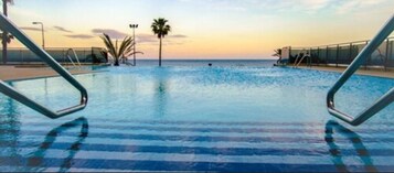 Una piscina techada, una piscina al aire libre, sombrillas