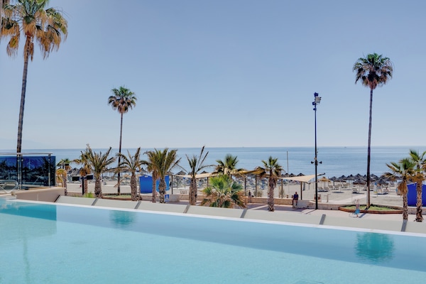 Una piscina techada, una piscina al aire libre, sombrillas