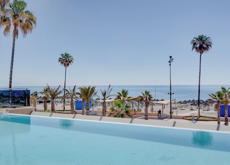 Una piscina techada, una piscina al aire libre, sombrillas