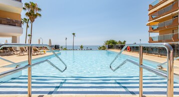 Una piscina techada, una piscina al aire libre, sombrillas