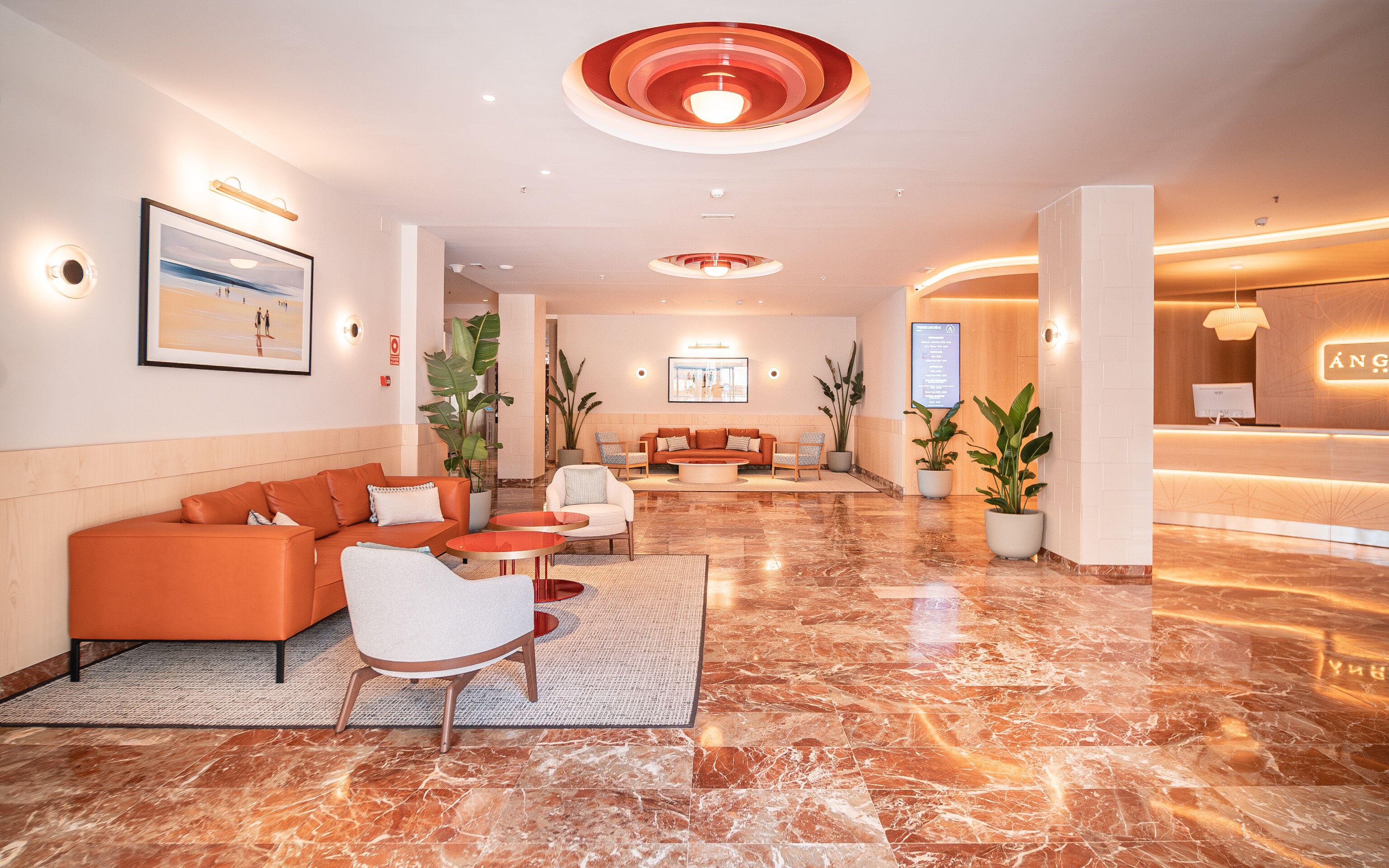 A spacious lobby with a reception desk, seating area, and a large framed picture on the wall.