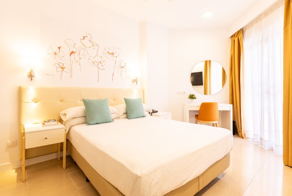 A hotel room with a large bed, bedside tables, a desk, a chair, a round mirror, and a wall art piece. - Hotel Angela - Adults Recommended (Fuengirola)