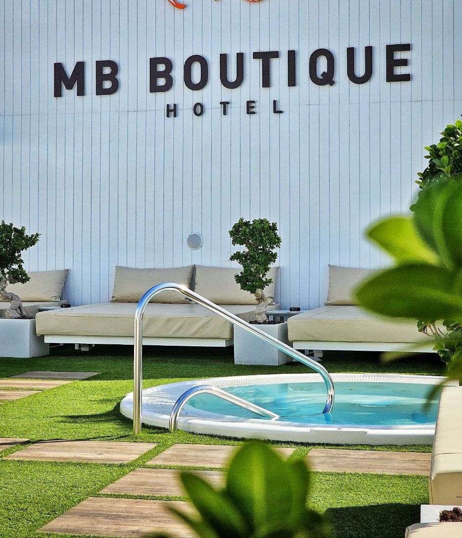 A pool area with a lounge chair and a sign for MB Boutique Hotel.