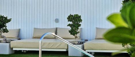 A pool area with a lounge chair and a sign for MB Boutique Hotel.