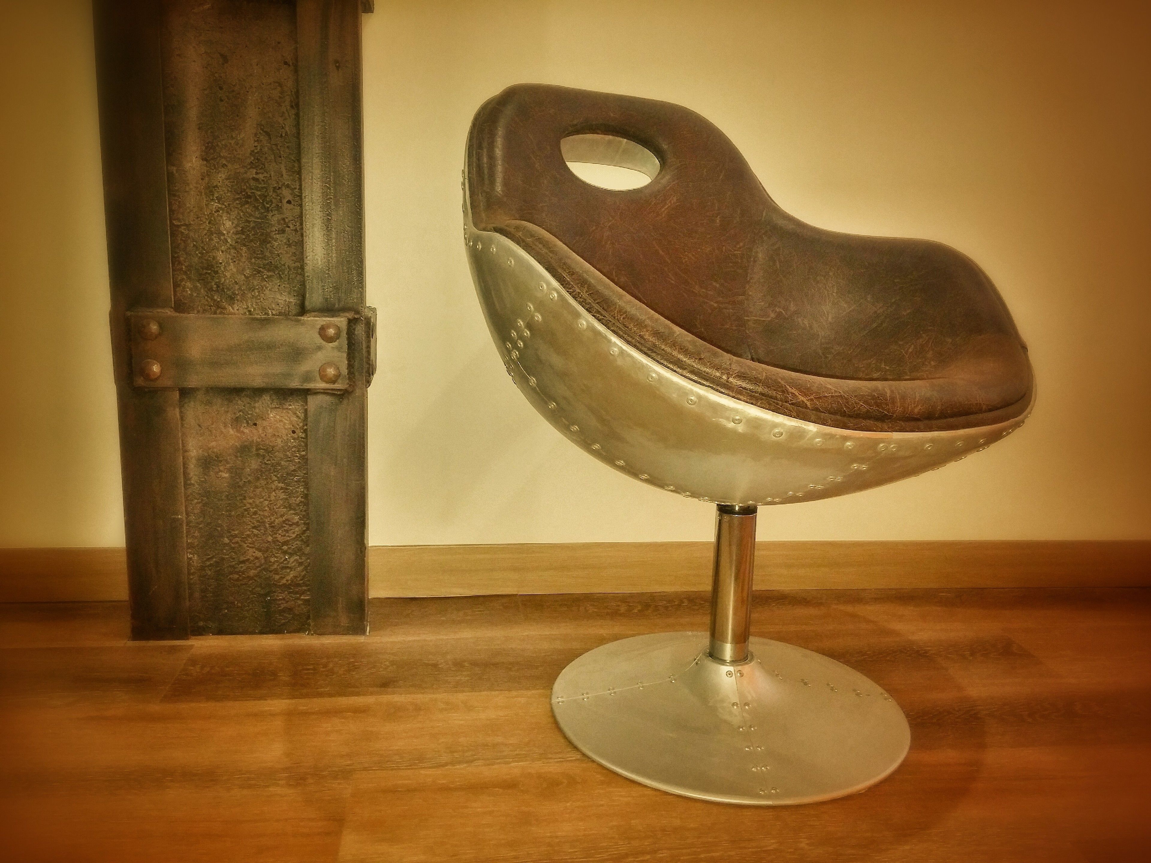 Una silla metálica antigua con asiento y respaldo de cuero, que presenta un corte circular.