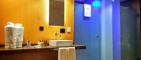 Un baño moderno con tocador de madera, un espejo grande y una cabina de ducha de vidrio.