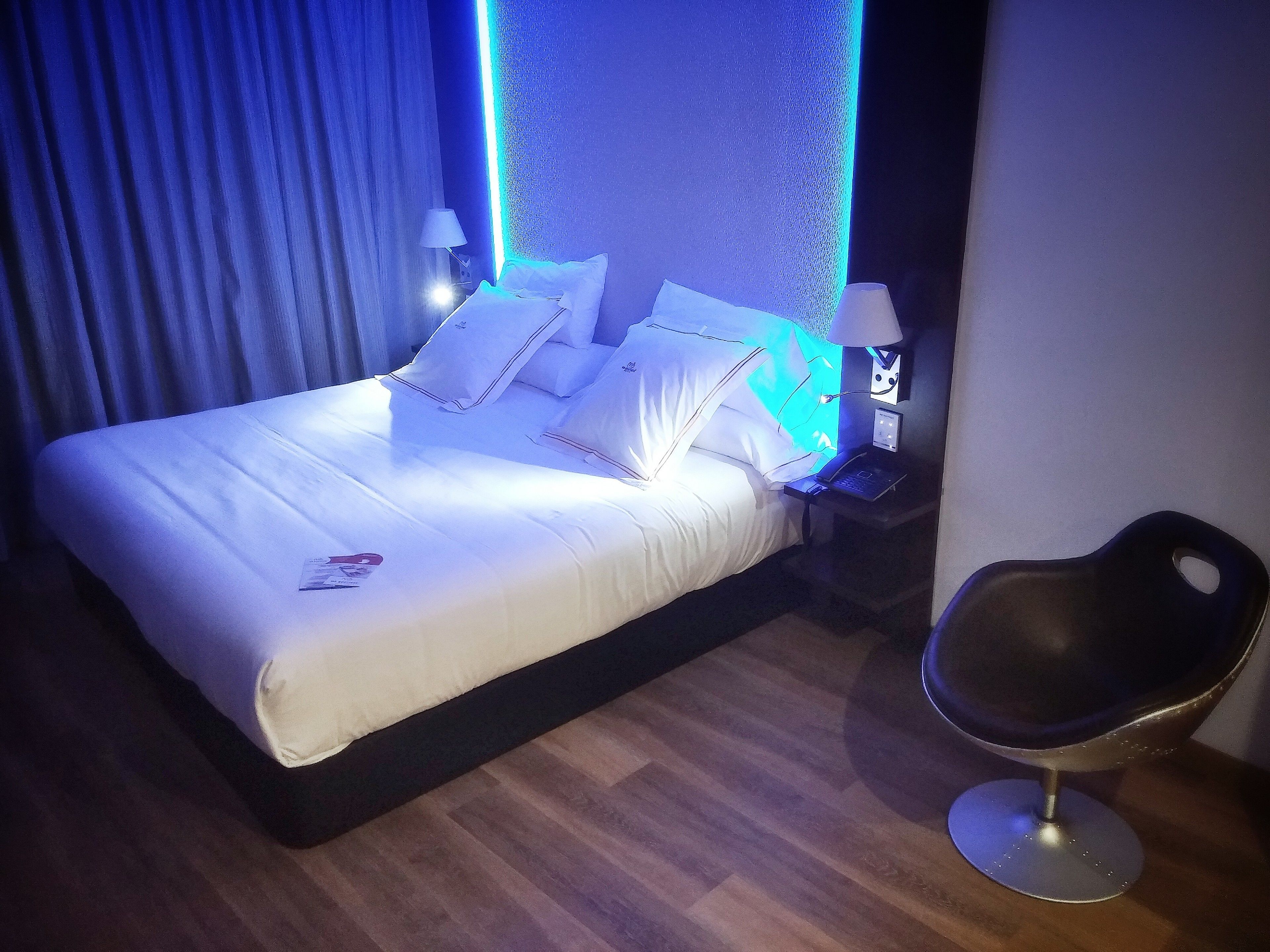 A hotel room with a bed, a nightstand, a laptop, and a chair.