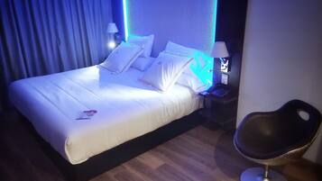 A hotel room with a bed, a nightstand, a laptop, and a chair.