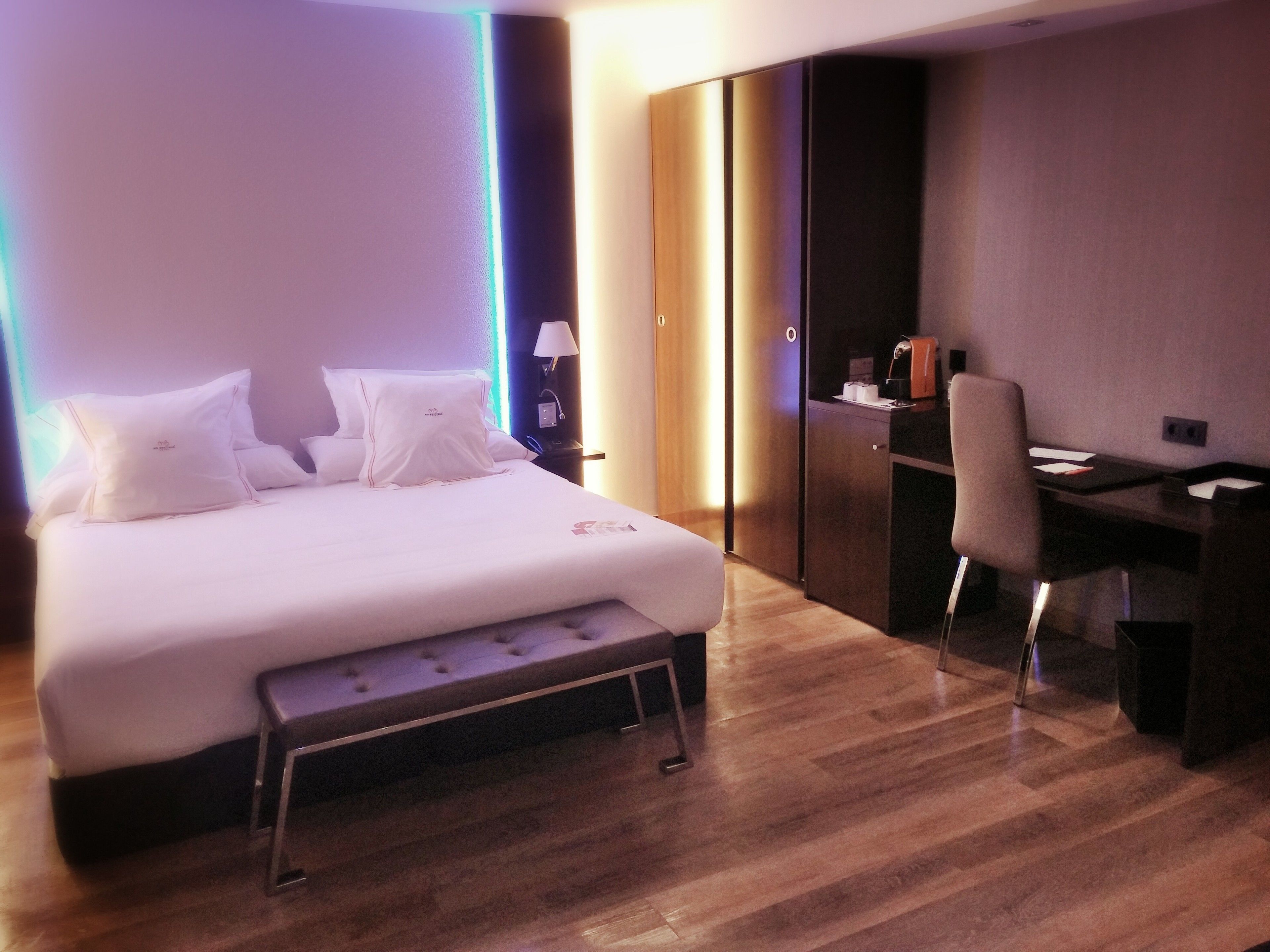 Une chambre d’hôtel moderne, dotée d’un grand lit, de tables de chevet, d’un bureau et d’une armoire.