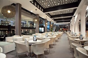 Un café moderne, situé à l’intérieur, avec des meubles en osier et des luminaires suspendus.
