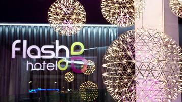 A hotel interior with spherical hanging light fixtures and a modern wall with illuminated letters spelling 'flash hotel'.
